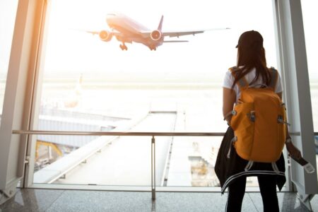 Traveler woman see the airplane at the airport window - Stopovers Paid By Carrier